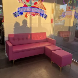Cute pink couches. there are chairs and tables on the other side of this wall