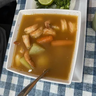 a bowl of soup with shrimp and vegetables
