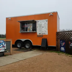 an orange food truck parked on the side of the road