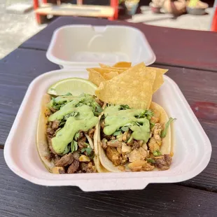 two tacos in a plastic container