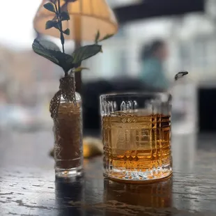 a glass of whiskey and a vase of flowers