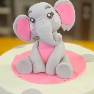 a baby elephant sitting on top of a cake