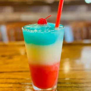 a colorful drink with a cherry on top
