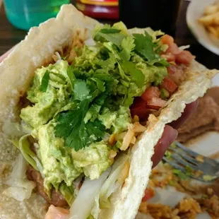 Corn tortillas with a side of rice, beans, guacamole, lettuce and tomatoes.  Perfection!!