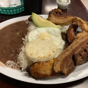 Bandeja Paisa, Steak, fried pork belly, sausage, fried yellow plantain, avocado, rice, beans, an arepa and a fried egg.