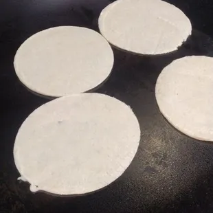 four tortillas cooking on a grill