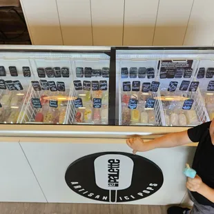 a young boy standing in front of an ice cream shop