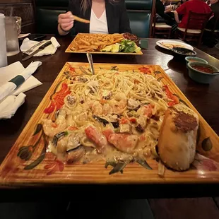 a woman sitting at a table with two plates of food