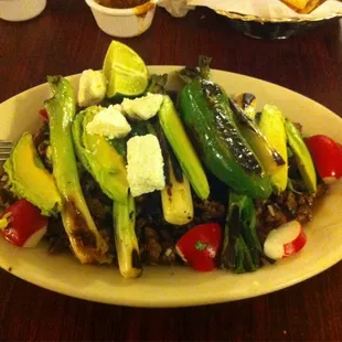 Sergio's Plate. Carne Asada over whole beans with grilled onions and avocado on top.