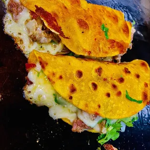 two quesadillas on a black plate