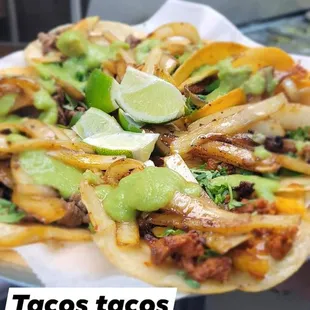 a plate of tacos with lime wedges