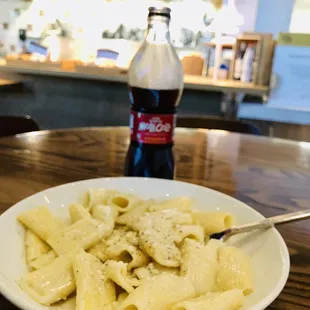 a plate of pasta and a soda