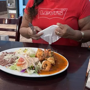a woman sitting at a table with a plate of food