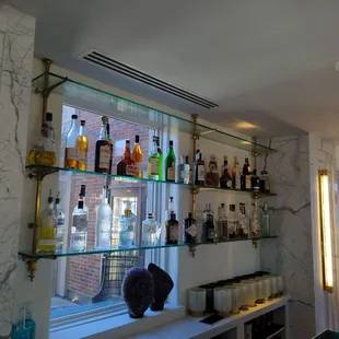 a shelf of liquor bottles on a window sill