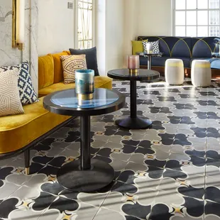 a living room with a yellow couch and a black and white patterned floor