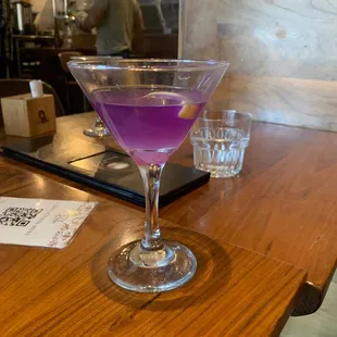 a purple cocktail in a martini glass
