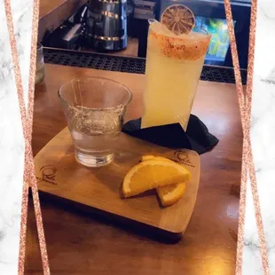 a glass of lemonade and a slice of orange on a cutting board