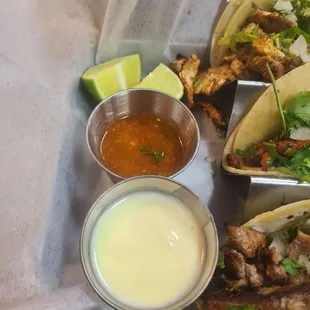 Lime, hot sauce and cheese dip  accompany street tacos