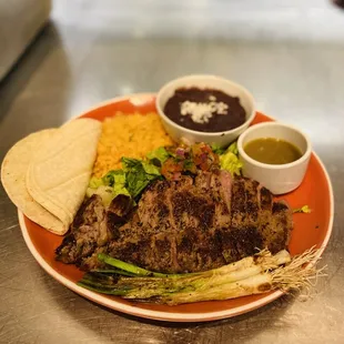 Carne asada plate, mexican rice, beans, corn tortilla and new york steak cooked to perfection.