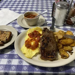 Scrambled eggs with salsa, new york strip steak, seasoned breakfast potatoes, and buttered raisin bread toast!
