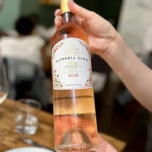 a person holding a bottle of rose wine