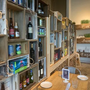 a wooden table and shelves filled with bottles of wine