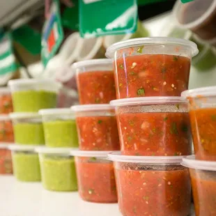 a row of plastic cups filled with salsa