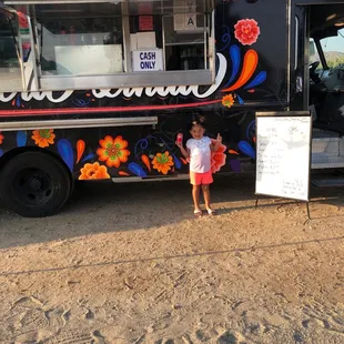 a little girl standing in front of a food truck