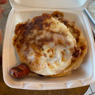 a sausage and cheese pizza in a styrofoam container