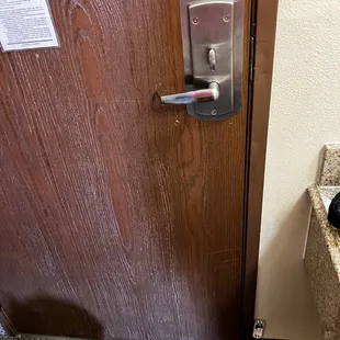 Hole near the floor showing exposed electronics for the door lock.