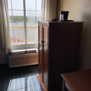 Morning sun shining through the window on armoire housing the fridge and microwave.