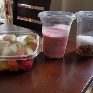 A wide variety of fresh fruit with a side of sweet cream and yogurt mixed and a side of coconut and granola mixed.