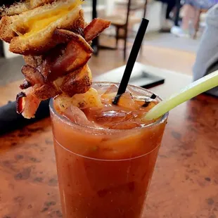 a glass of bloody bloody with bacon and a grilled cheese sandwich