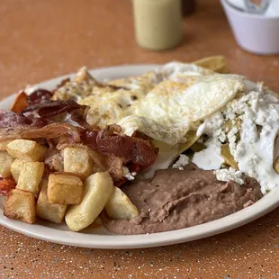Mixed chilequiles plate with over easy eggs and side of bacon.