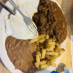 Carne Guisada, two eggs over easy, potatoes, refried beans and flour tortillas.
