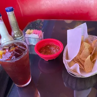 a table with chips, salsa, and a drink