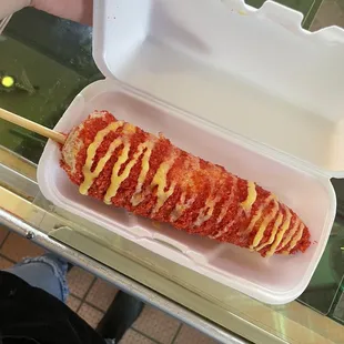  a person holding a container with a hot dog in it