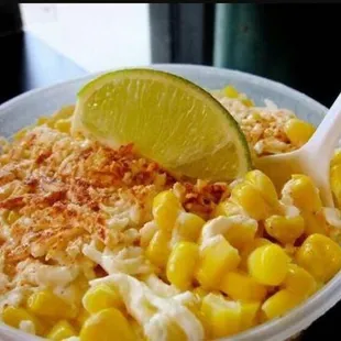 a bowl of corn and a lime slice