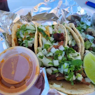 All homemade corn tortillas- al pastor, carne asada, and carnitas with diced onion, cilantro, lime, and hot sauce.
