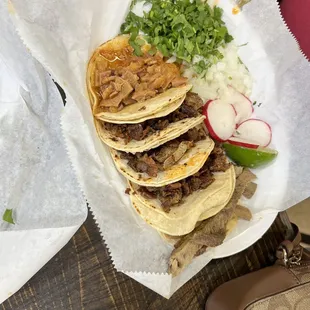 a plate of tacos with onions and radishes