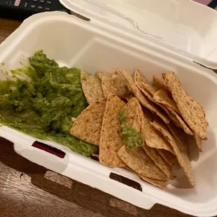 chips and guacamole in a styrofoam container