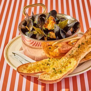 a bowl of musselling and bread on a plate