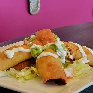 FLAUTAS: Fried corn tortilla rolled with beef or chicken,topped whith lettuce,fresh Mexican cheese sour cream serve over guacamole.