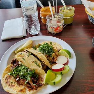 Tacos  in a thick soft shell. Disposable utensils in the complimentary sauces. Spicy peppers with onions as a side.