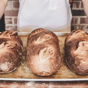 a baker holding three loaves