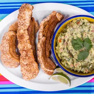 a white plate with a bowl of guacamole and churros