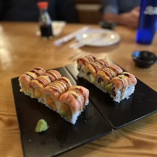 two sushi rolls on a black plate