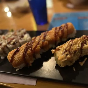 three sushi rolls on a black plate