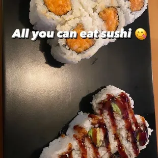 two sushi rolls on a black plate