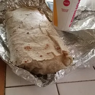 The Triple X burrito next to a large soda. Thing is massive and only 10 DOLLARS.